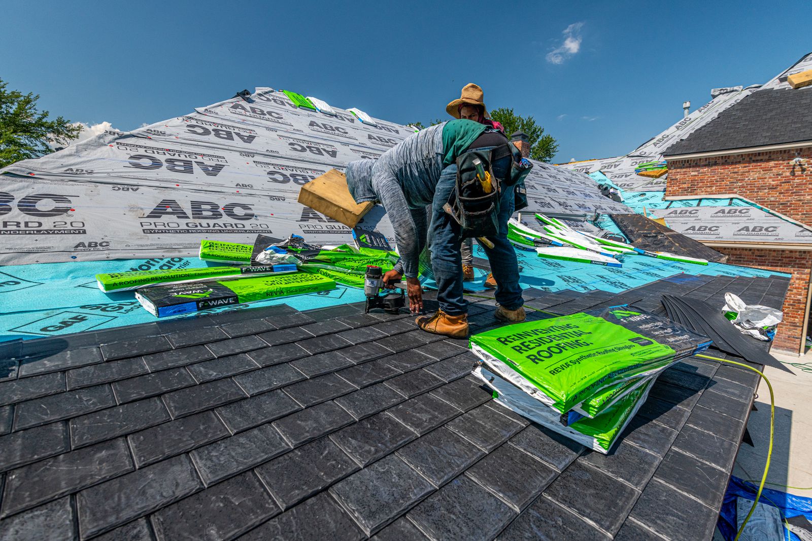 Slater laying new slate over fresh underlayment on a brick house