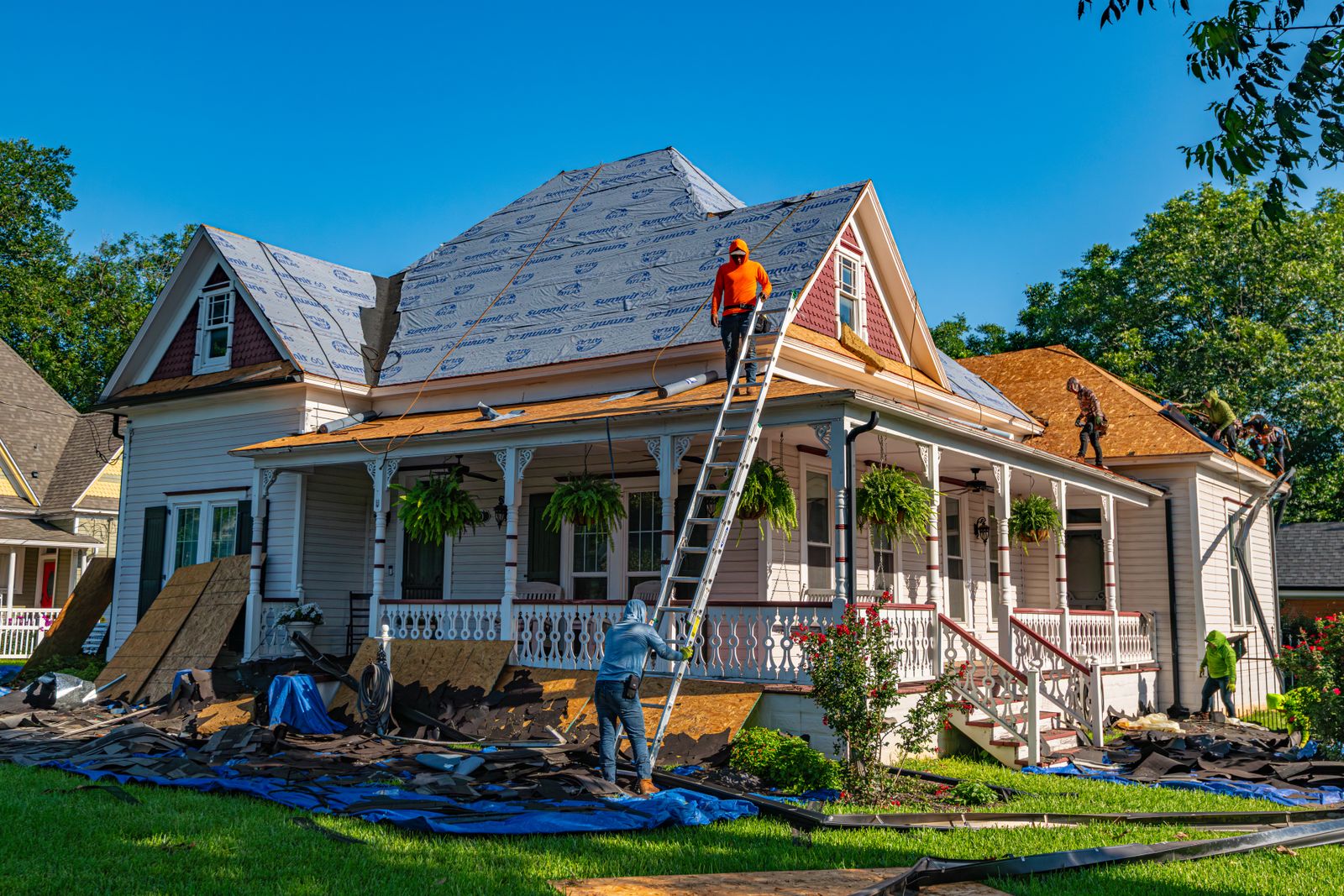 Roofers restoring the roof of a historic porch-front house