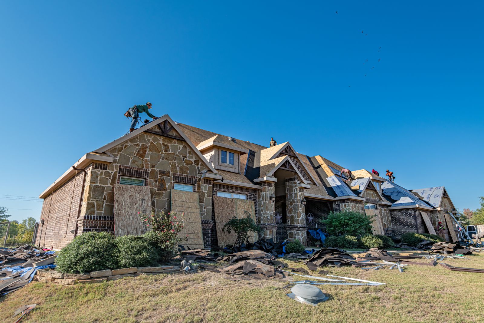 Crew installing a new roof on a large brick house