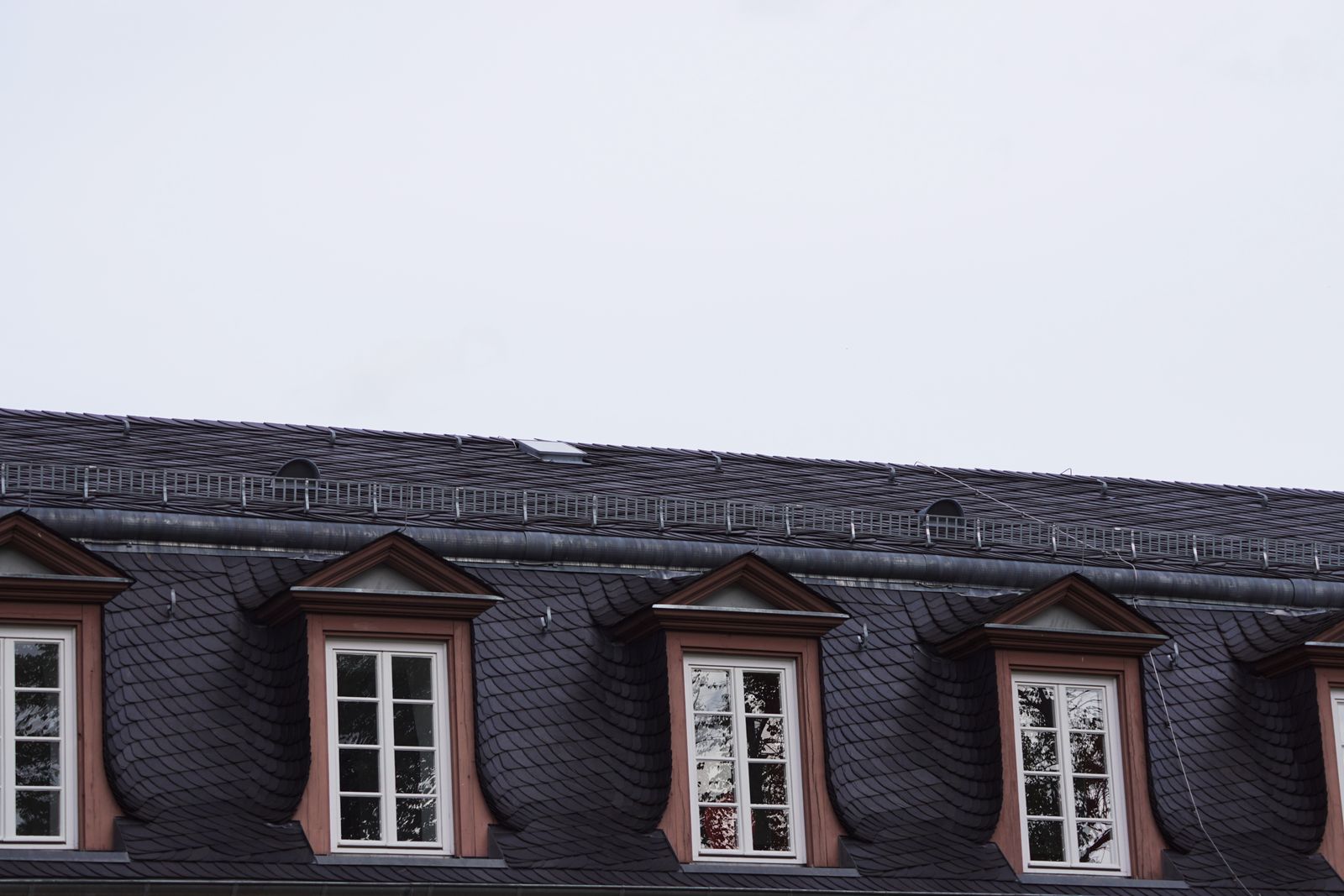 Slate mansard roofline with copper-trimmed dormer windows